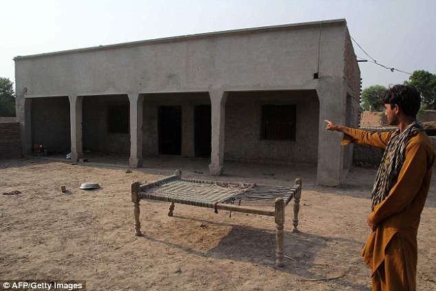 a pakistani villager poses as he points to a house where a teenage girl was raped