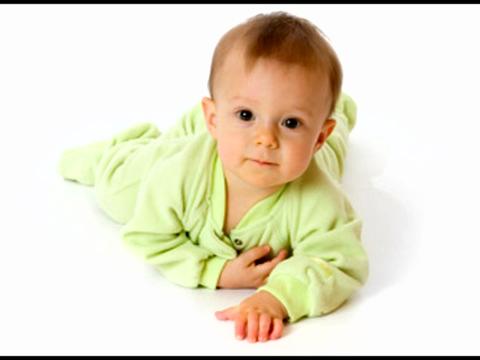baby in a green sleep suit crawling on the floor