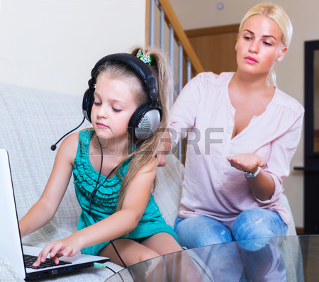 frustrated young woman catching her smiling daughter watching forbidden site online