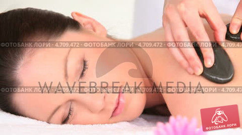 good looking woman receiving a massage with pebbles preview