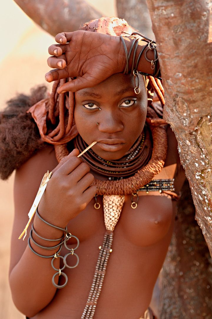 himba young woman leaning on tree in the shade of namibia africa
