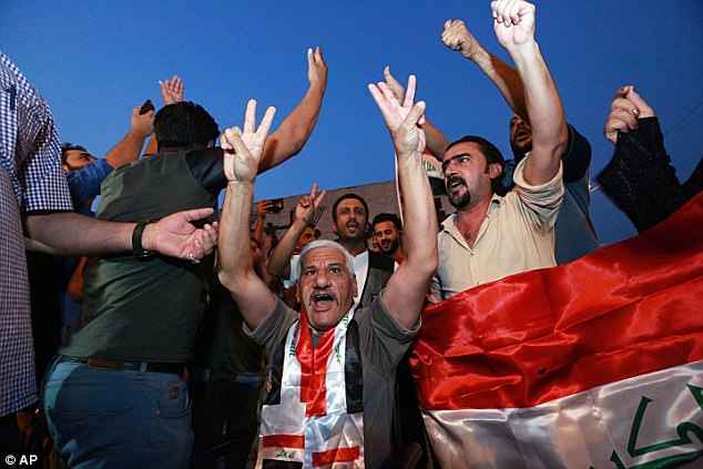 iraqis celebrate in tahrir square while holding national flags as they wait for the final announcement