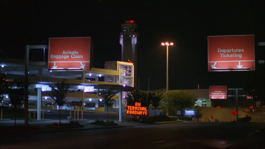 night airport departure arrival signs above cars driving in control tower background