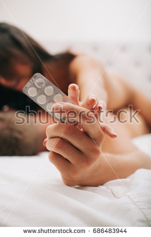 stock photo man taking a pill before sex young man sitting on bed with birth control pills and vaginal