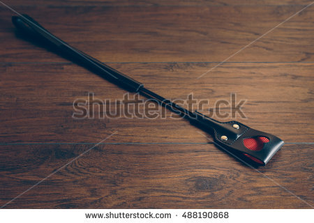stock photo riding crop bondage sex gear with heart shaped spanking end on wood background with copy space