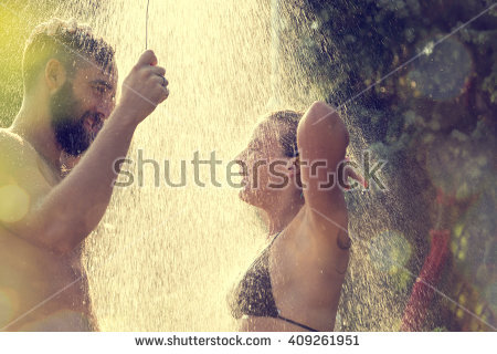 stock photo young couple taking a shower on the beach after swimming