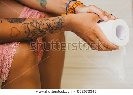 stock photo young woman sitting on the toilet and holding a roll of toilet paper