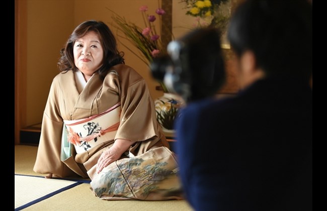 tomita sits on a tatami floor while posing for a photographer as she